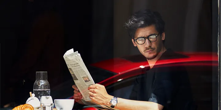 Man Reading Newspaper with Red Light Streak, dark-mode, photographic, dark