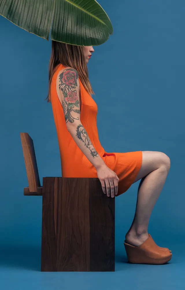 Woman in Orange Outfit with Leaf Overlay, photographic, minimal, vibrant