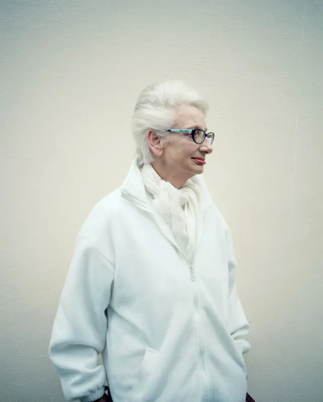 Portrait of an elderly woman in white, minimal, light-mode, light