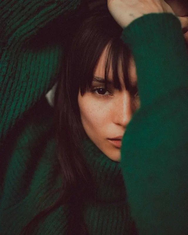 Portrait of a woman in green knitwear, photographic, organic, dark