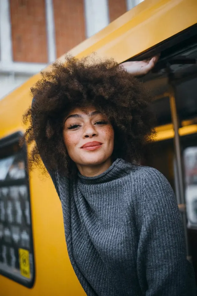 Portrait of a woman with afro hair in yellow vehicle, photographic, vibrant
