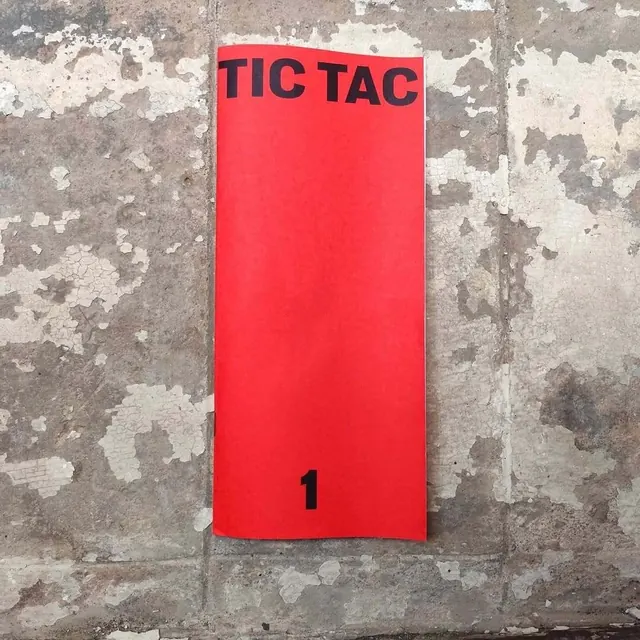 Red wayfinding sign with bold sans-serif on weathered concrete, minimal, brutalist, dark
