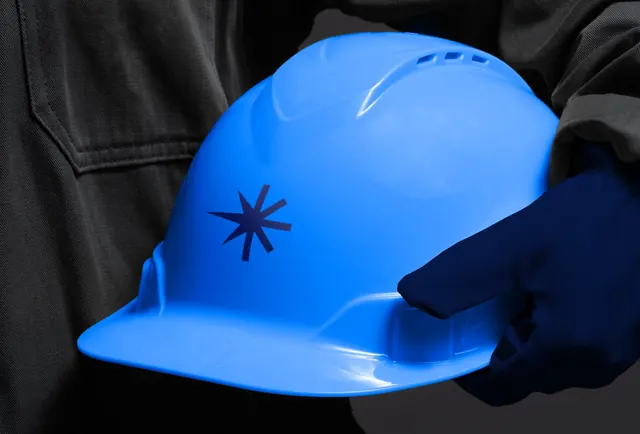 Bright blue hard hat held by dark glove, photographic, minimal, dark