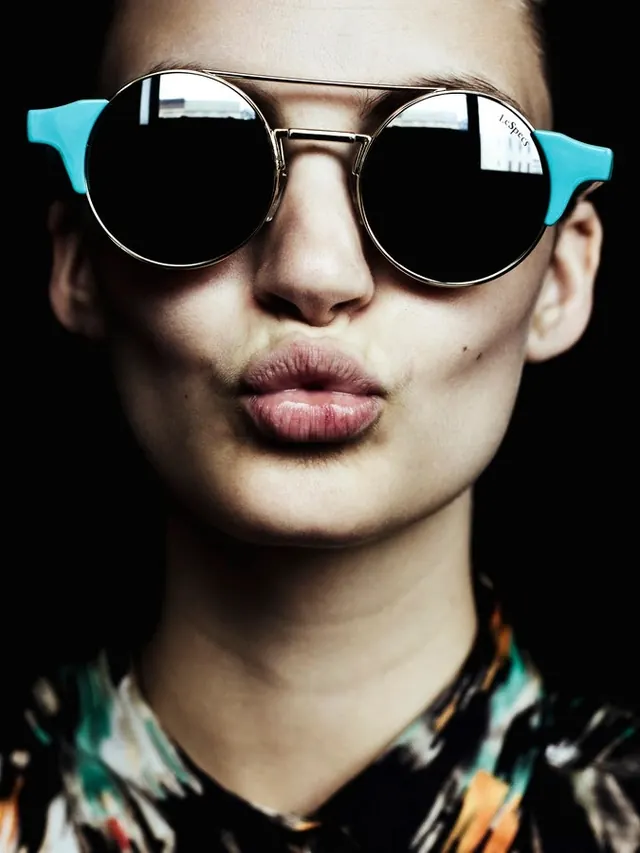 Portrait of a person with blue-rimmed sunglasses, photographic, high-contrast