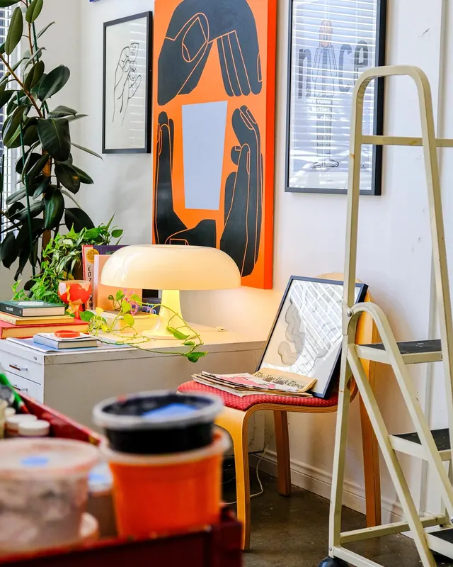 Creative studio desk with orange artwork and plants, photographic, playful, light