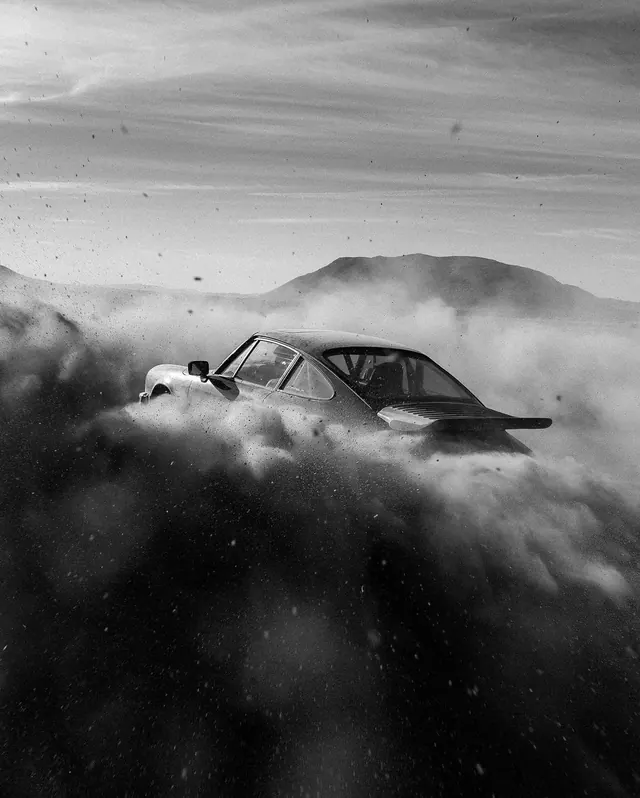 Classic sports car sliding through a cloud of dust in monochrome, photographic, cinematic, dark