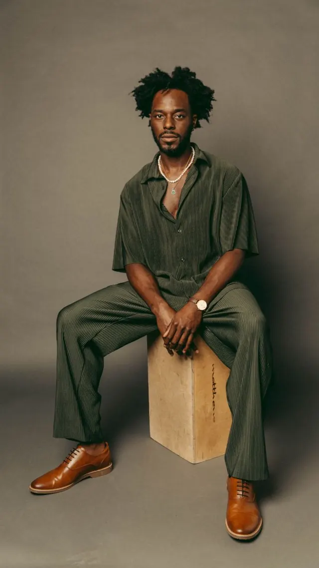 Seated portrait in sage green texture suit, photographic, editorial, warm