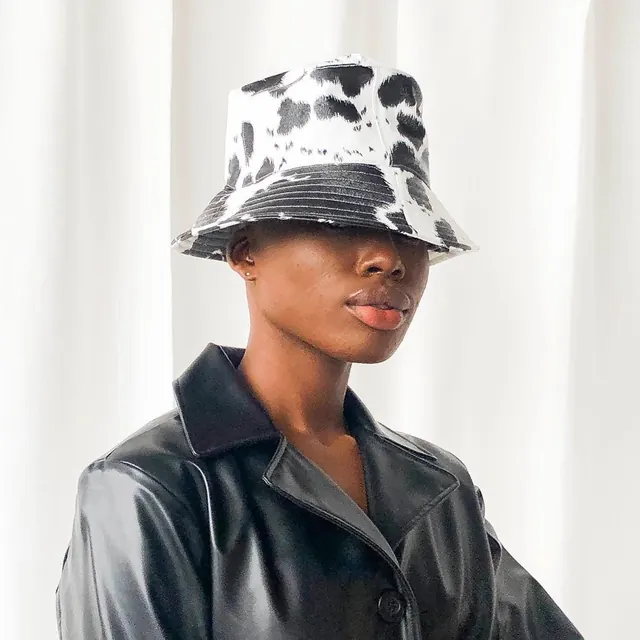 Studio portrait with cow-print bucket hat and leather jacket, photographic, playful, monochrome