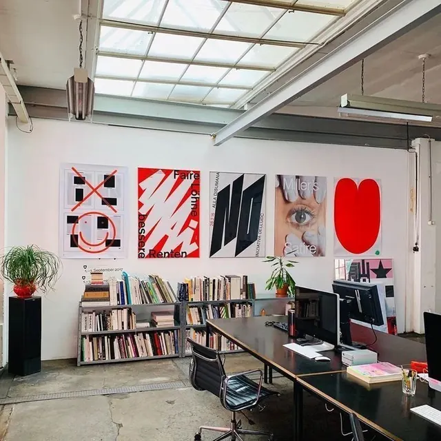Design studio workspace with red accent wall graphics, minimalist, geometric, light