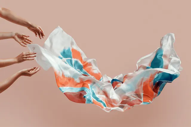 Hands holding flowing fabric in motion, photographic, organic, warm