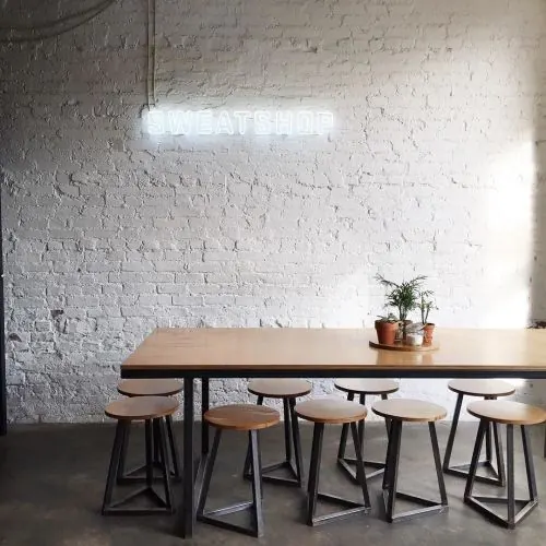 \"Sweatshop\" neon sign cafe interior, minimal, industrial, light
