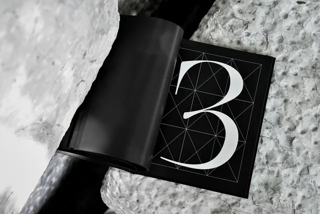 Open type-specimen book on rock, editorial, minimal, monochrome
