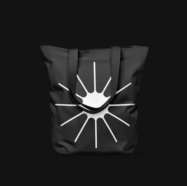 Black tote bag with abstract starburst icon, minimalist, geometric, dark