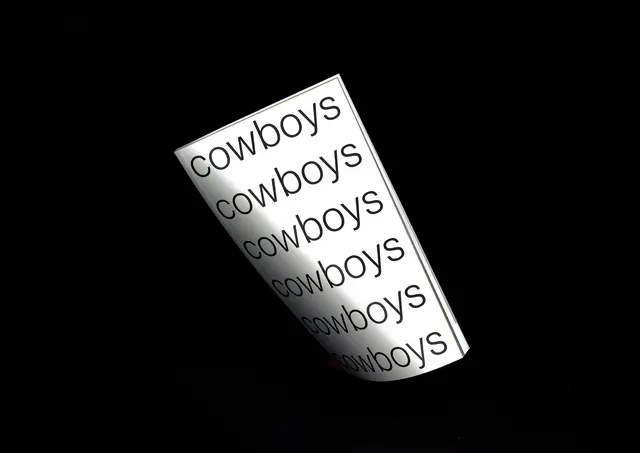 Cowboys repeated word on metallic plaque, minimal, monochrome, dark