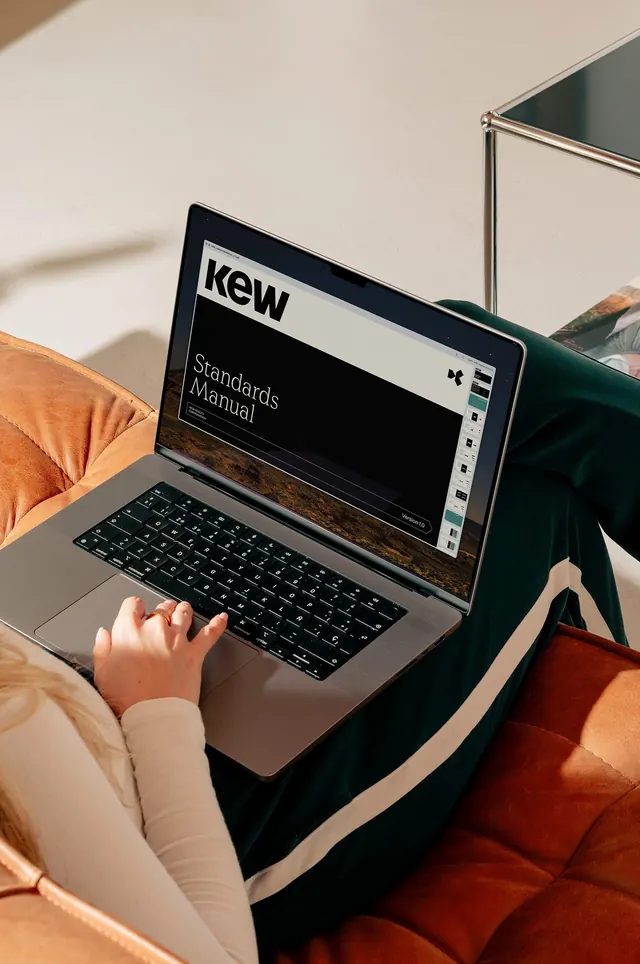 Laptop with KEW Standards Manual in warm setting, photographic, lifestyle, light