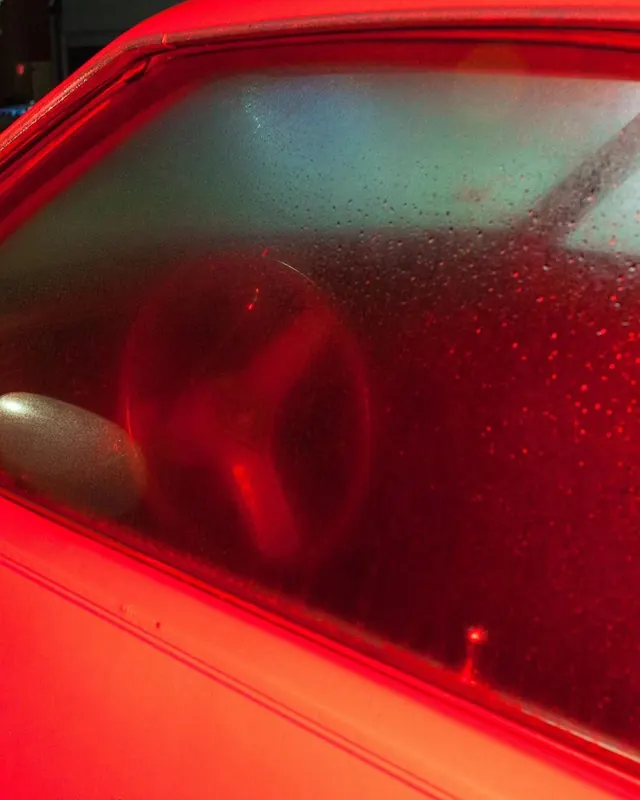 Red-lit fogged car window close-up, photographic, minimal, vibrant
