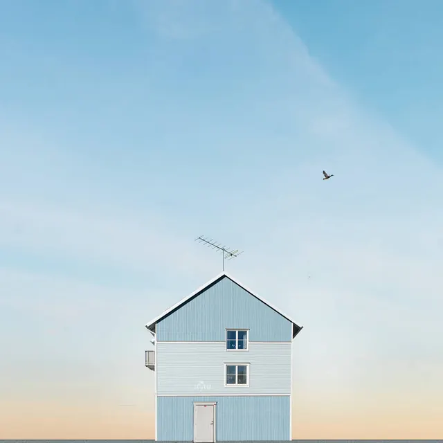 Narrow blue house under vast sky, minimal, photographic, pastel