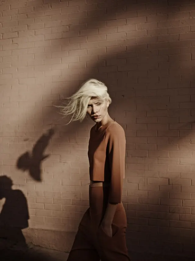 Terracotta fashion portrait with bird shadow, editorial, photographic, warm