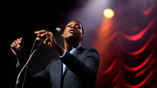 Performer at microphone in warm stage lighting, photographic, warm, warm