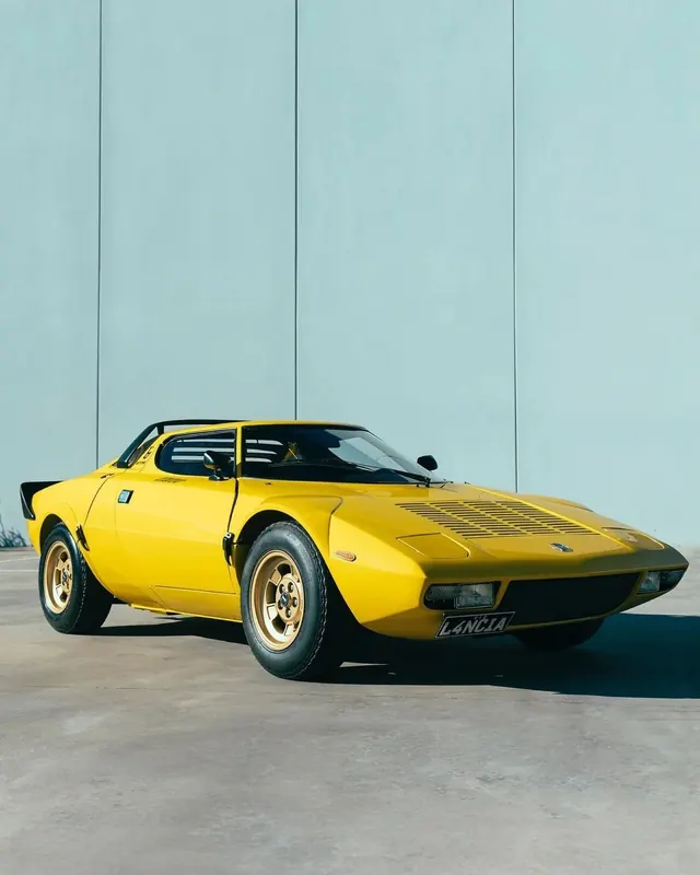 Yellow Lancia Stratos against pale wall, photographic, minimal, vibrant