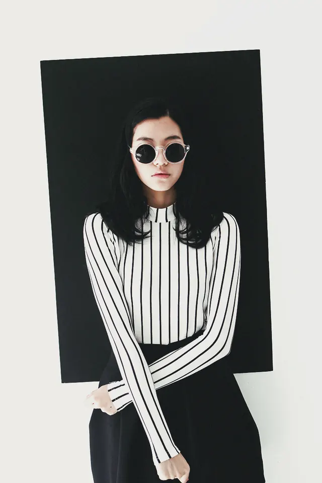 High-contrast minimalist portrait with oversized sunglasses, photographic, editorial, dark