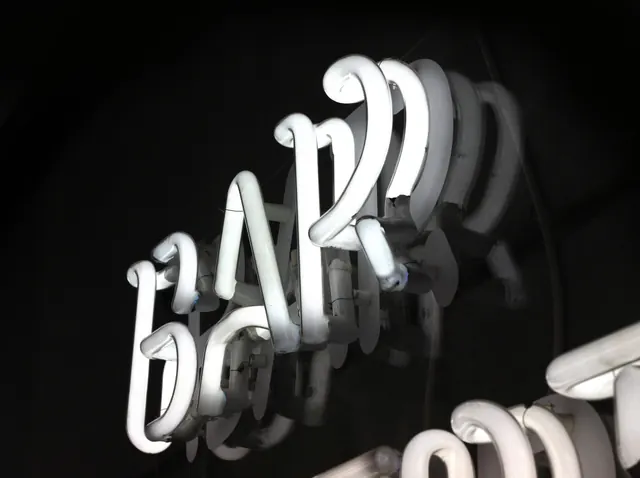 White BAR neon sign close-up, dark-mode, photographic, dark