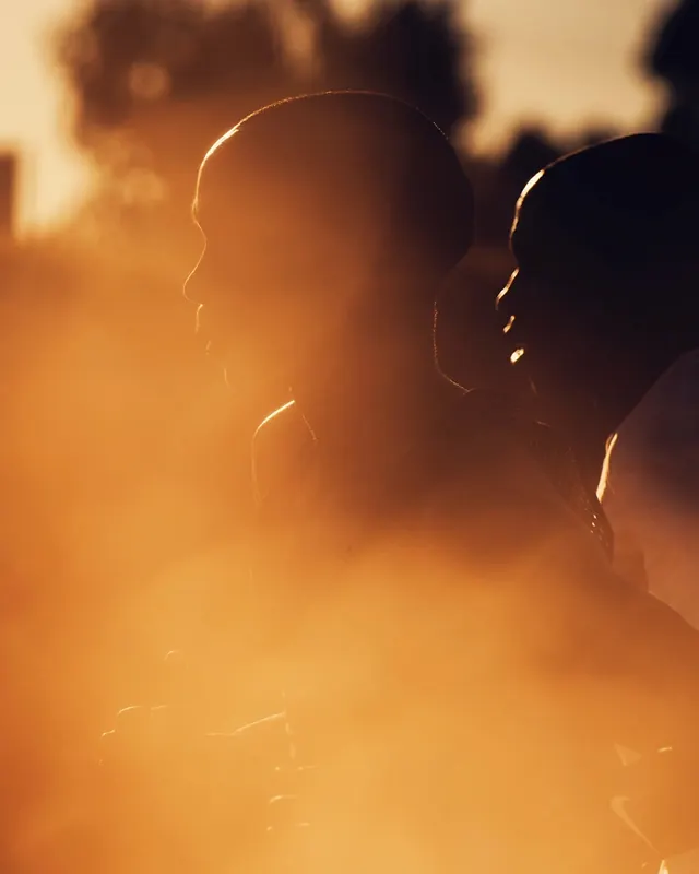 Golden-hour silhouettes in dust, photographic, editorial, warm