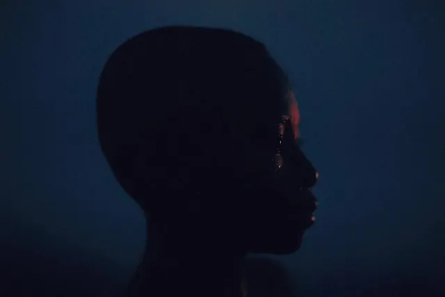 Low-key blue profile portrait, photographic, editorial, dark