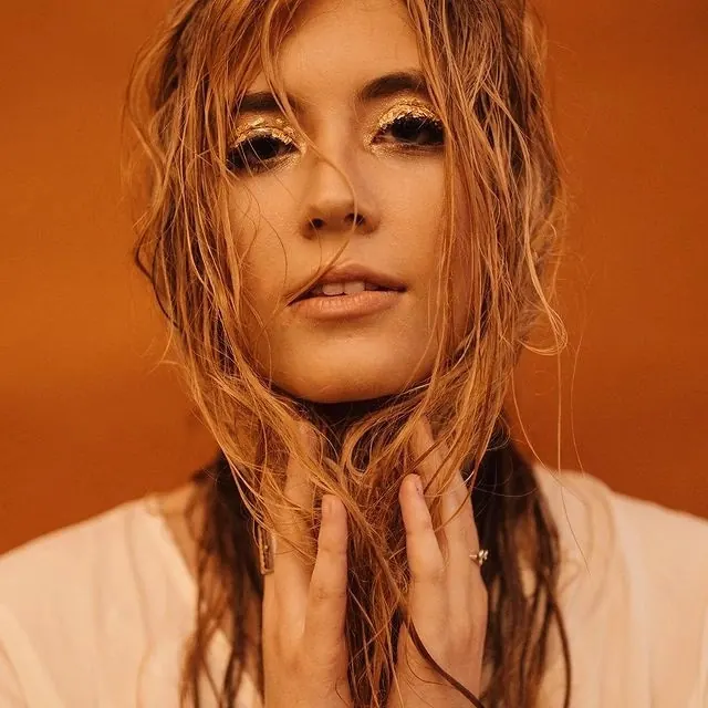 Portrait with gold eyeshadow and warm orange background, photographic, warm, warm