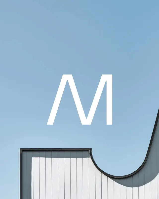 Large M letterform architectural sign, minimal, photographic, light