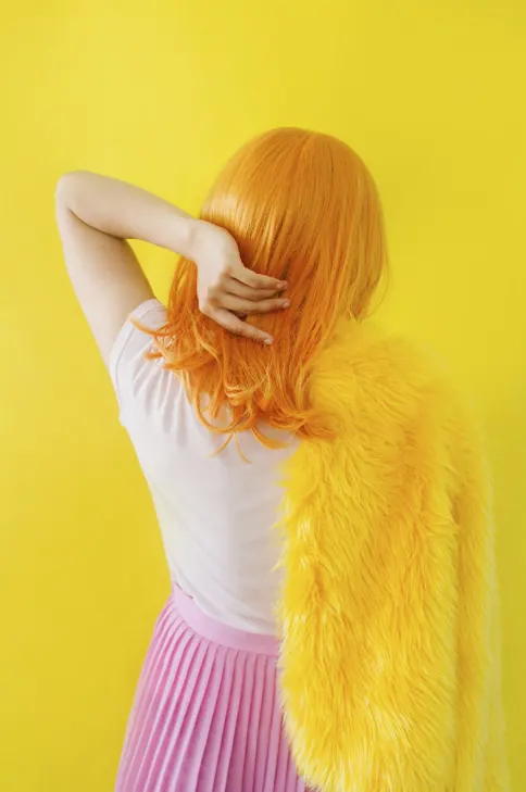 Figure in bright yellow with orange hair and pink skirt, photographic, playful, vibrant