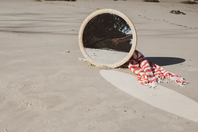 Woven mirror on beach sand with fabric composition, photographic, organic, earthy