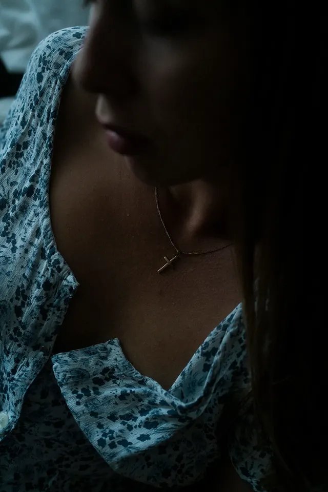 Moody portrait with textured fabric and warm jewelry, photographic, minimal, dark