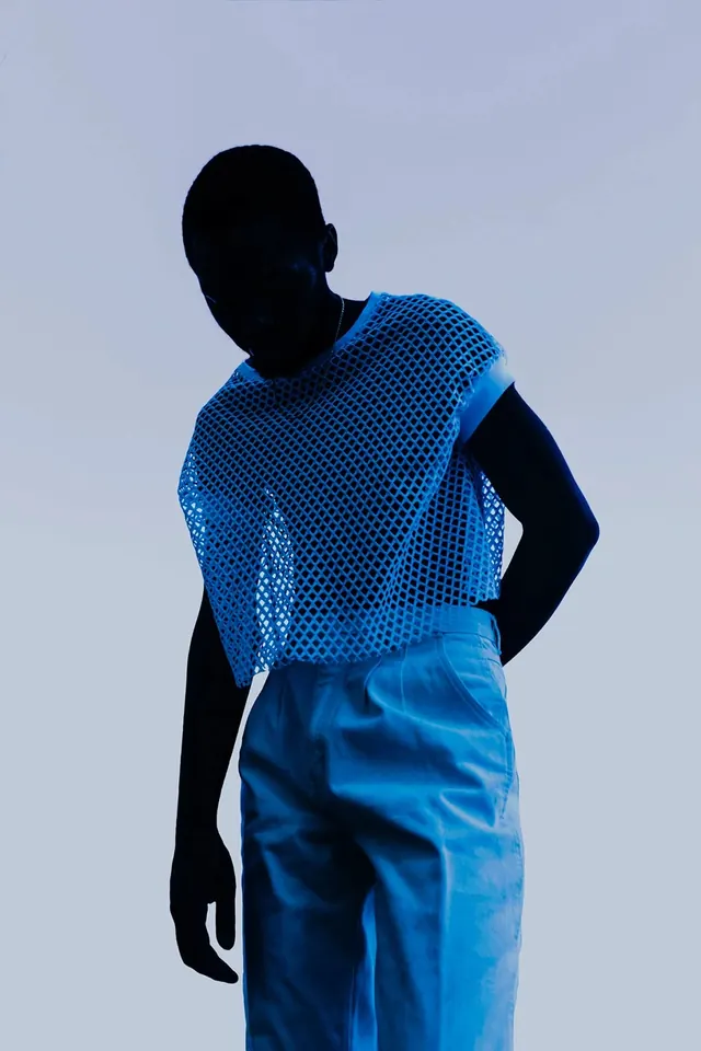 Silhouetted figure in bright blue patterned garment, photographic, technical, vibrant
