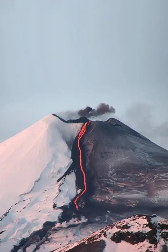 Volcanic cone with lava flow and snow cap, photographic, dramatic, vibrant