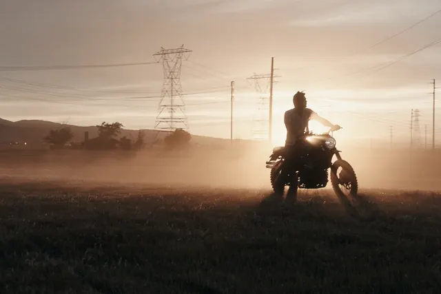 Motorcycle silhouette at sunrise against utility lines landscape, photographic, minimalist, warm