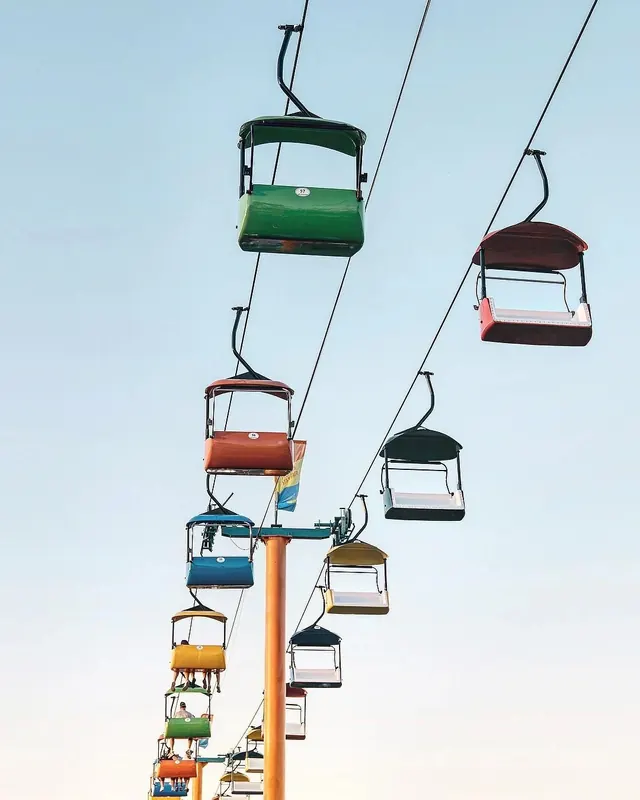 Colorful ski lift chairs against light sky, photographic, minimal, light