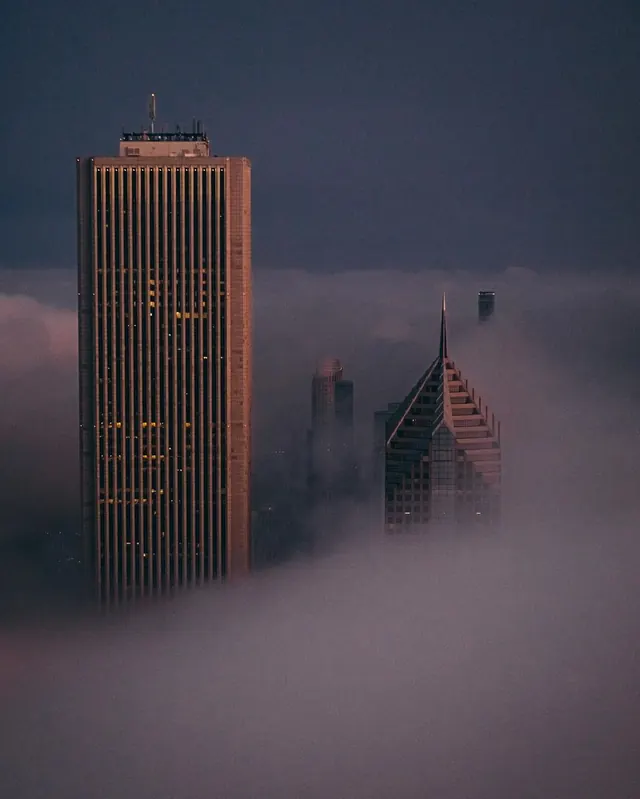 Chicago skyline buildings emerging from fog at dusk, photographic, editorial, cool