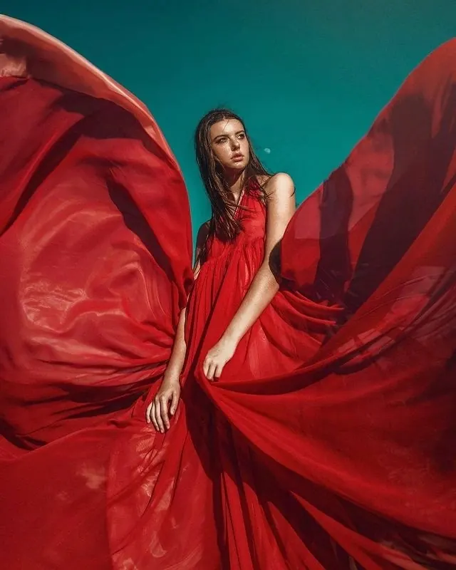 Flowing fabric portrait against teal background, photographic, editorial, vibrant
