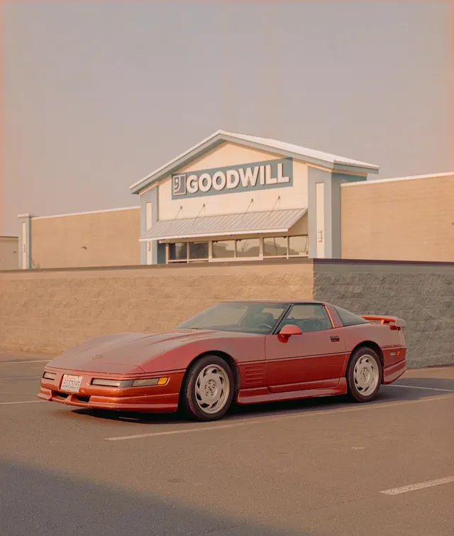 Red sports car at Goodwill storefront, photographic, retro, warm