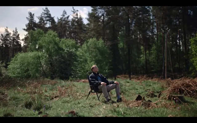 Seated figure in forest clearing landscape, photographic, documentary, earthy