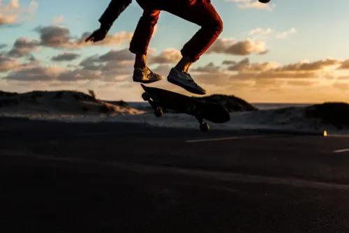 Runner on beach at golden hour with skateboard, photographic, dynamic, warm