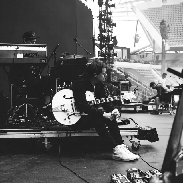 Black and white photograph of musician on stage with Gretsch guitar, photographic, monochrome, dark