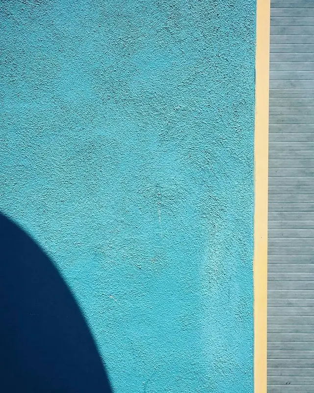 Architectural photograph of turquoise textured wall with shadow and yellow stripe, photographic, minimal, vibrant