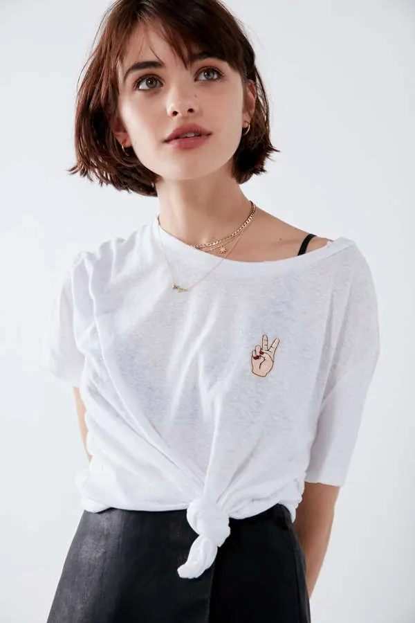 Model wearing white t-shirt with embroidered peace hand gesture, photographic, minimalist, light