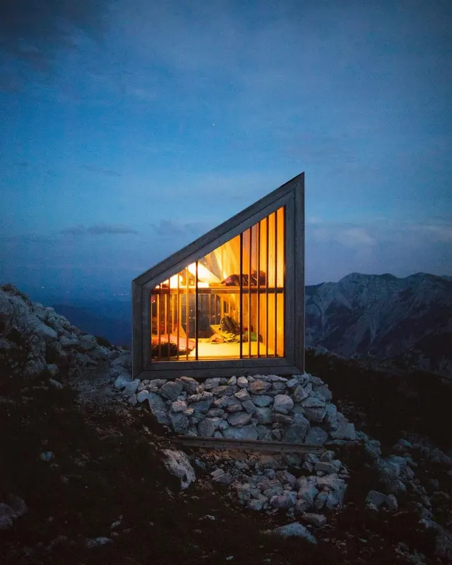 Mountain shelter at dusk with interior glow, photographic, technical, cool