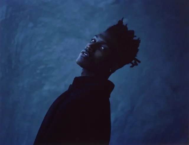 Silhouette portrait looking up against blue background, photographic, dark-mode, cool