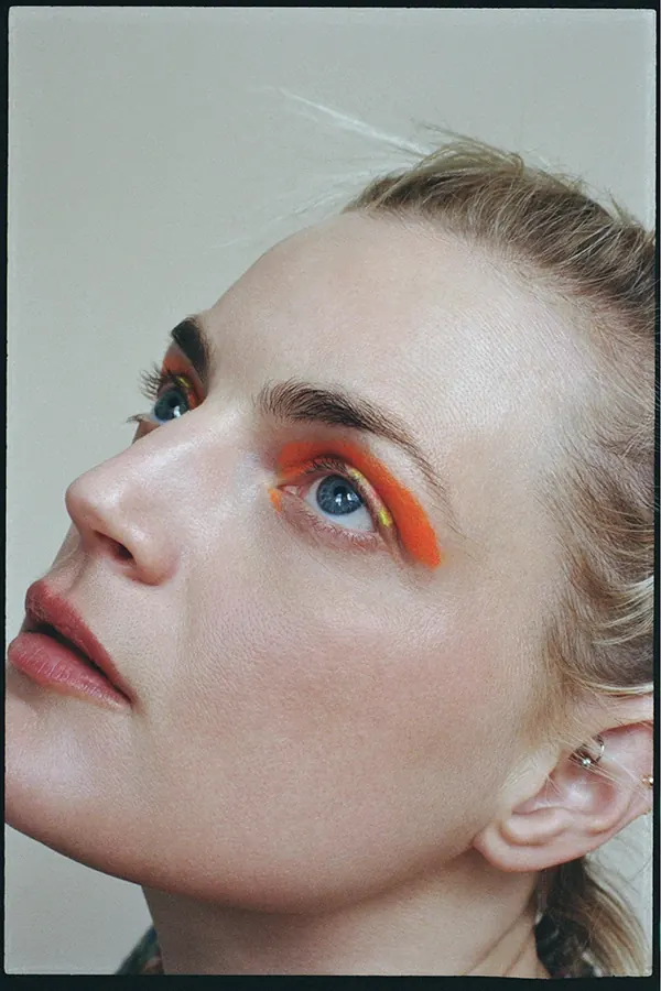 Beauty portrait with bold orange eyeshadow, photographic, professional, warm