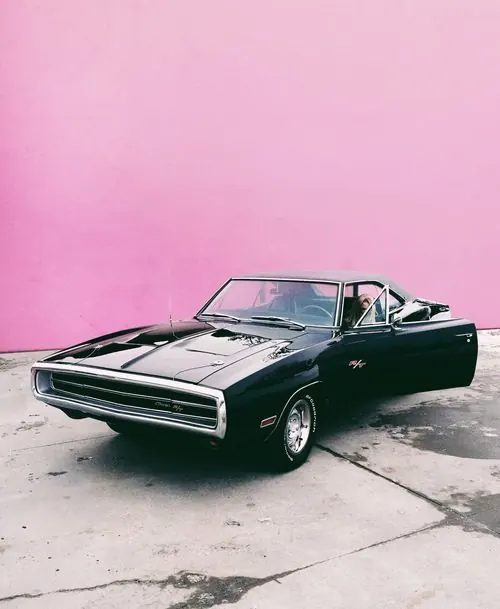 Vintage muscle car against pink wall, photographic, retro, vibrant