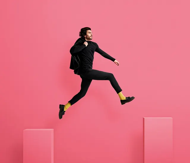 Person jumping in black outfit with yellow accent, photographic, bold, vibrant